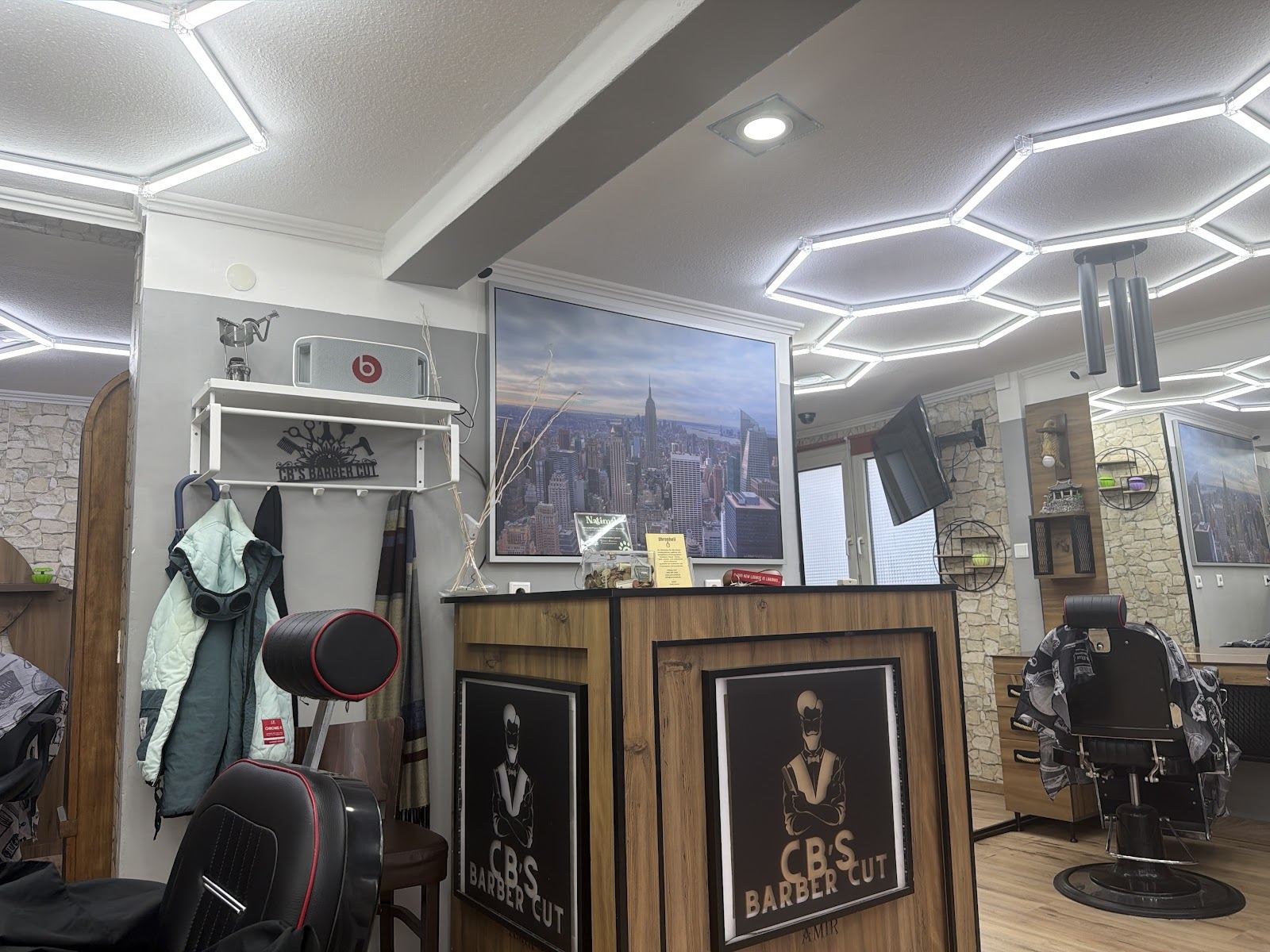 Innenansicht von C.B's Barber Cut in Groß-Gerau: Barberstühle unter der Wabendecke, Empfangstresen mit Logo